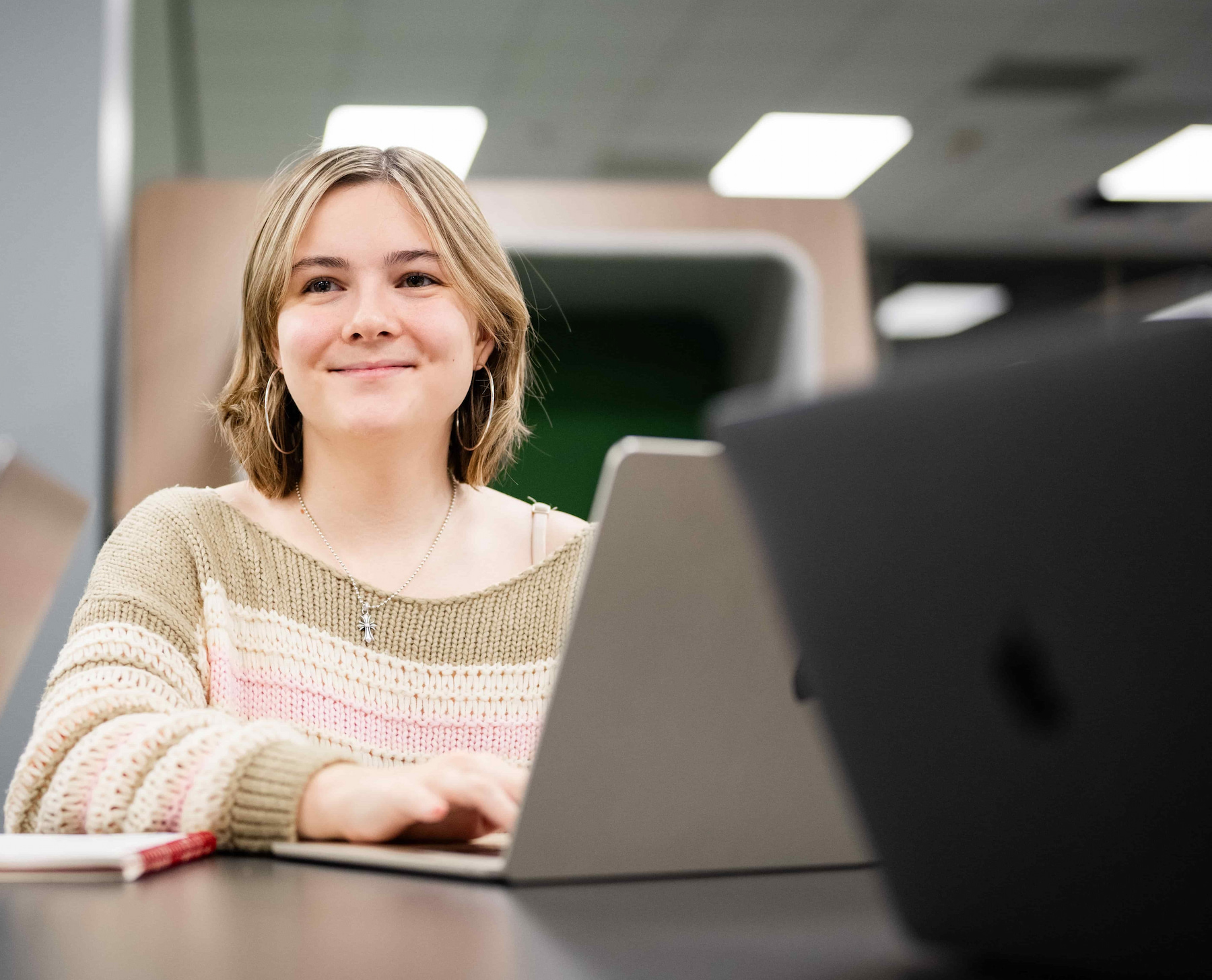 A student sitting at a desk working on a laptop