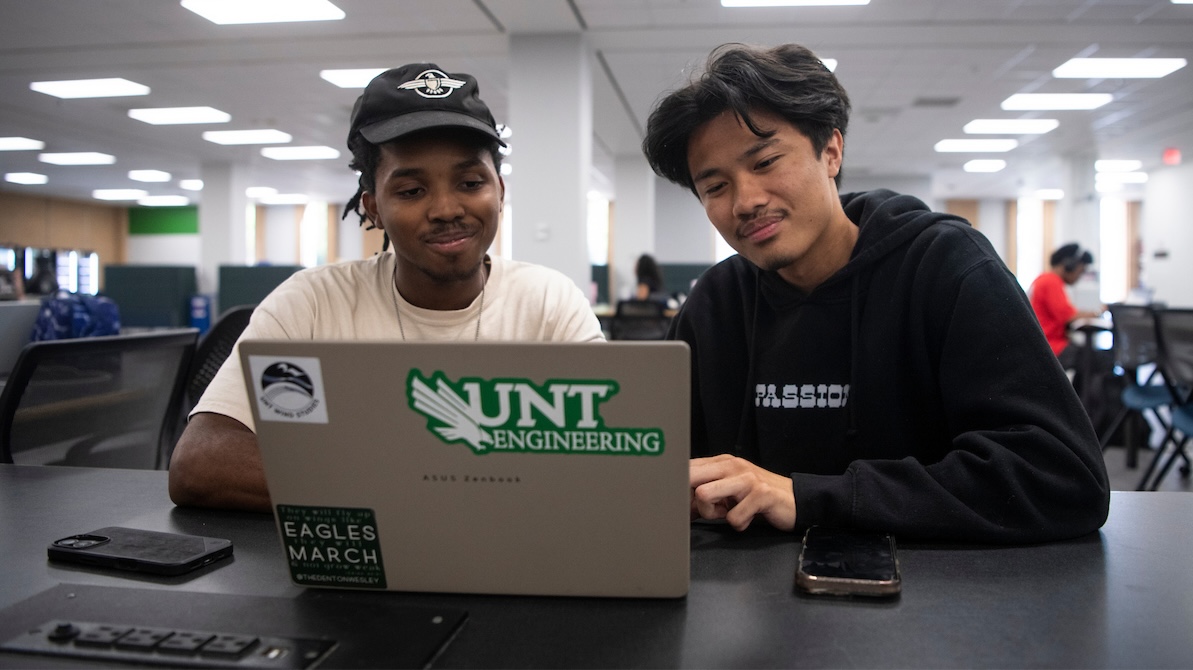 Two students with looking at a laptop in front of them in a UNT building