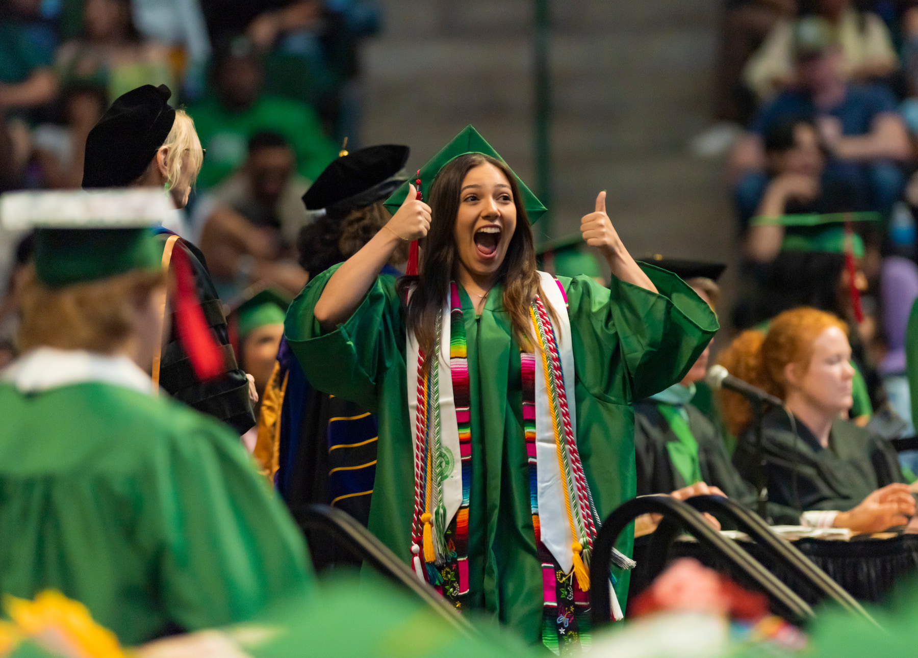 Graduate walking across the stage with a thumbs up