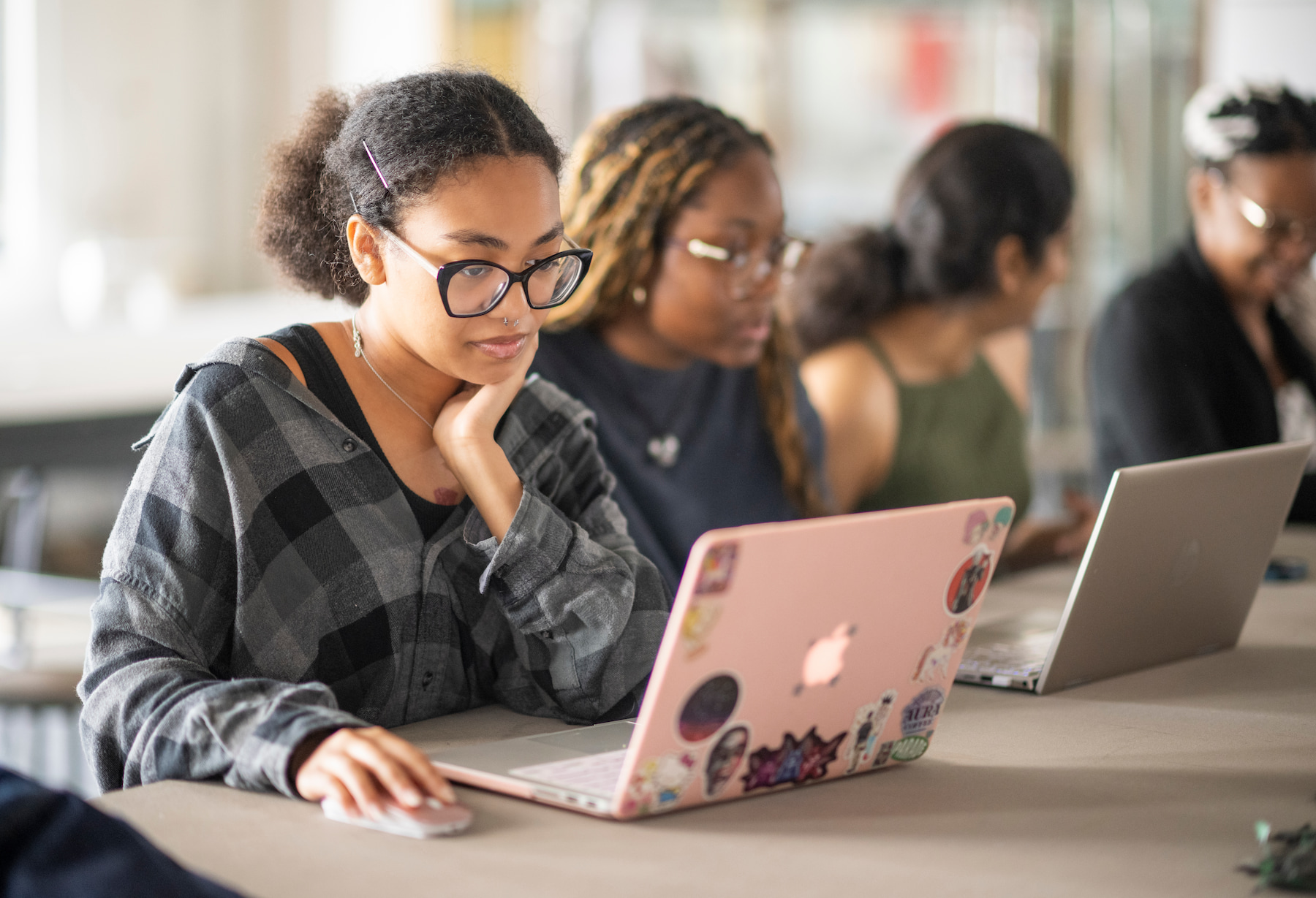 Student looing on her computer with other students around her in a class