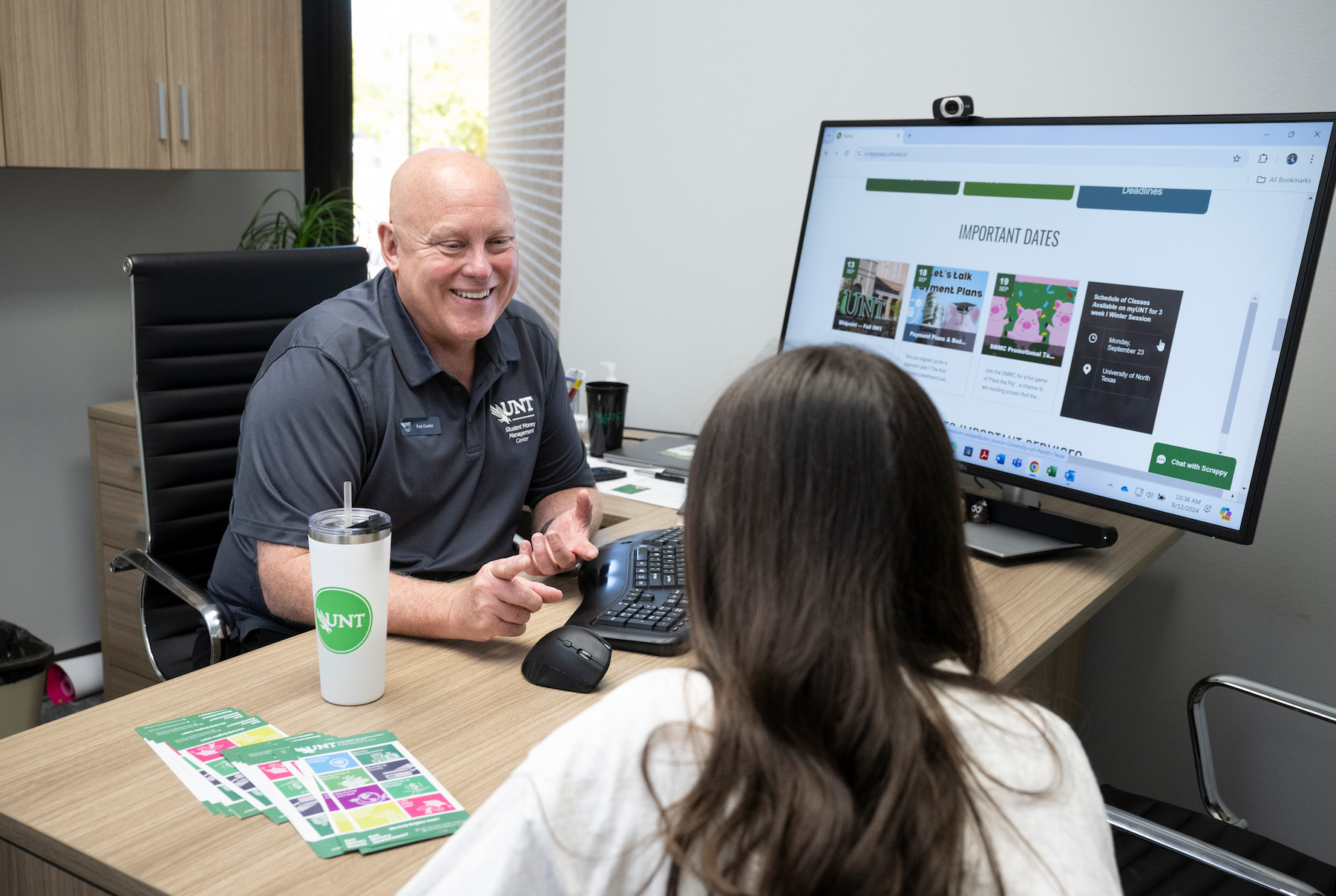 Advisor helping a student with campus resources in an office . 